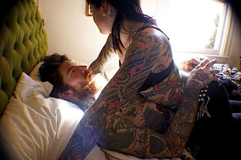Две татуированные любовницы по очереди сосут большой член бородатого мужика